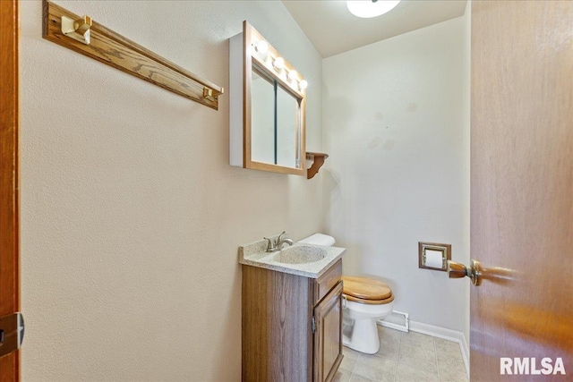 half bath with toilet, vanity, and baseboards