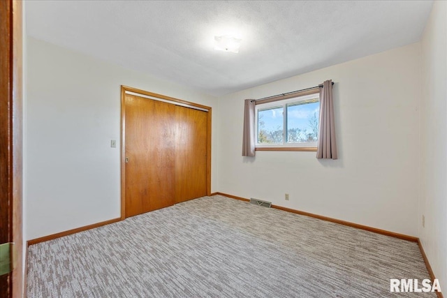 unfurnished bedroom with a closet, visible vents, carpet, and baseboards