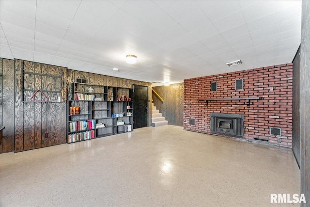 unfurnished living room with wood walls, speckled floor, and stairs