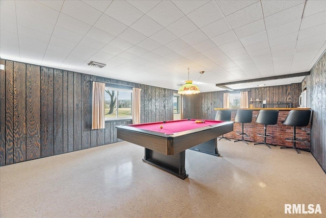 recreation room featuring wooden walls, speckled floor, visible vents, pool table, and bar area