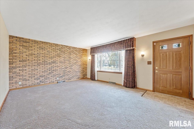 interior space with carpet flooring, visible vents, baseboards, and brick wall