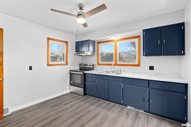 kitchen featuring ceiling fan, electric stove, blue cabinets, and a sink