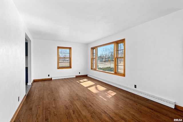 spare room with baseboards, dark wood-type flooring, and baseboard heating