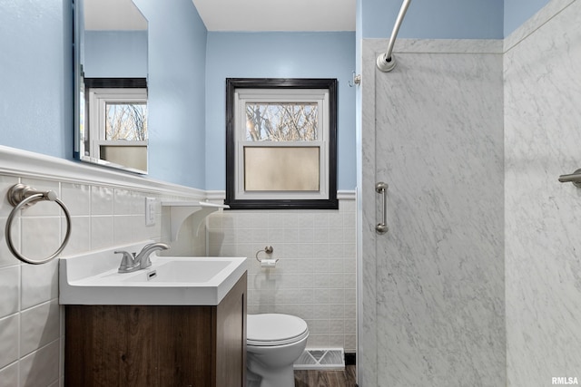 bathroom featuring vanity, tile walls, toilet, and walk in shower