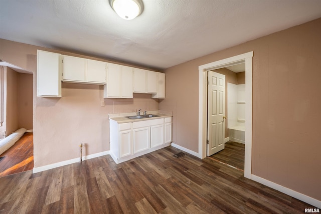 kitchen featuring a sink, baseboards, dark wood-type flooring, and white cabinets