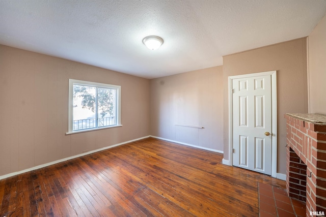 unfurnished room with a textured ceiling, baseboards, and hardwood / wood-style floors