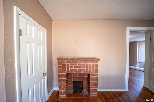 interior details featuring baseboards, a textured ceiling, wood finished floors, and a fireplace