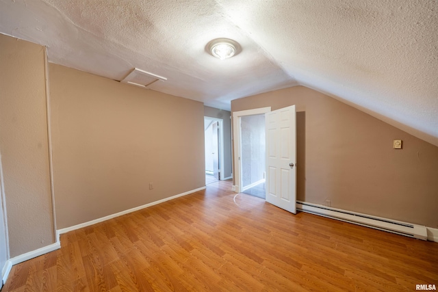 additional living space with attic access, lofted ceiling, light wood-style floors, a textured ceiling, and a baseboard radiator