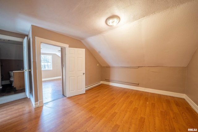 bonus room featuring light wood-style flooring, a textured ceiling, baseboards, and a baseboard radiator