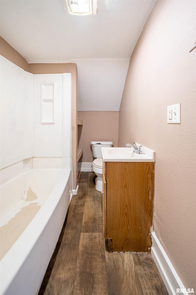 bathroom featuring toilet, a washtub, wood finished floors, baseboards, and vaulted ceiling