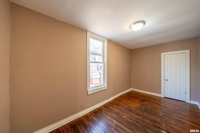 unfurnished room with a textured ceiling, dark wood-type flooring, and baseboards