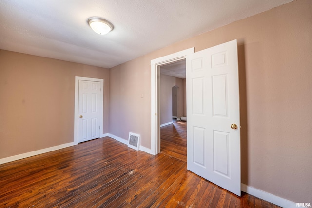 empty room with visible vents, baseboards, and dark wood-type flooring