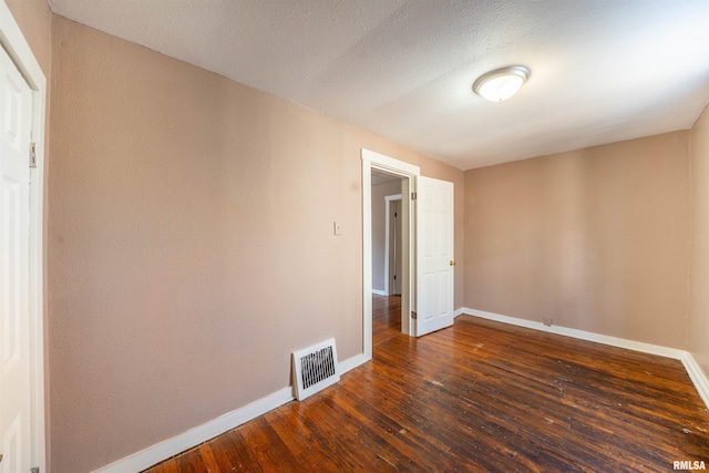 unfurnished room with dark wood-type flooring, baseboards, visible vents, and a textured ceiling