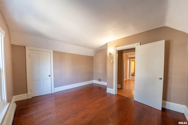 unfurnished bedroom featuring wood-type flooring, baseboards, and vaulted ceiling