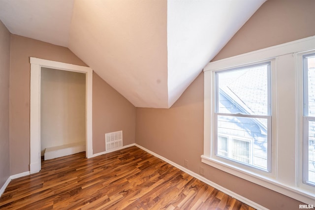 additional living space featuring visible vents, baseboards, wood finished floors, and vaulted ceiling