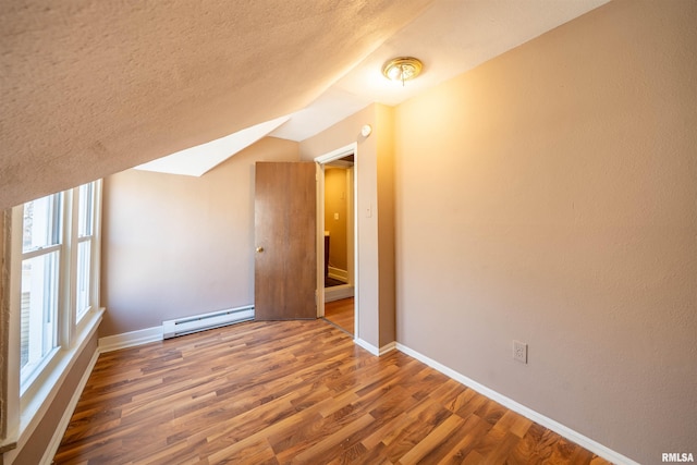 bonus room featuring wood finished floors, baseboards, lofted ceiling, a textured ceiling, and baseboard heating