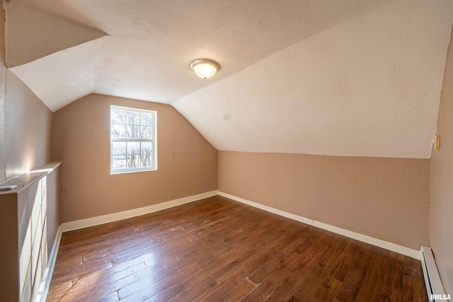 additional living space featuring hardwood / wood-style flooring, a baseboard heating unit, a textured ceiling, baseboards, and vaulted ceiling