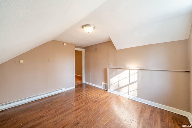 bonus room featuring baseboards, visible vents, vaulted ceiling, wood-type flooring, and baseboard heating