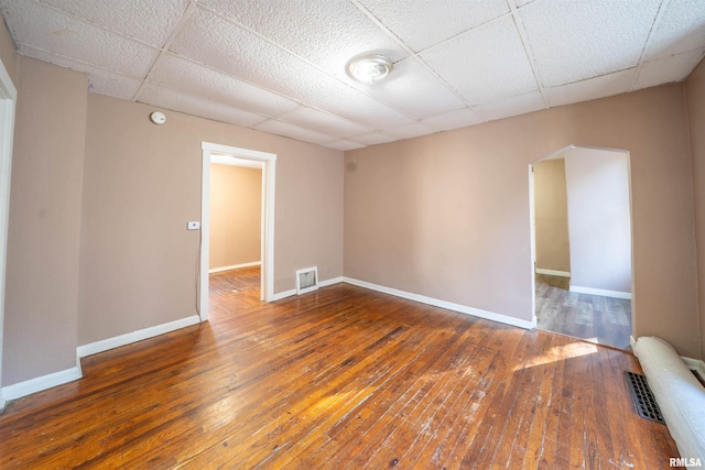 empty room with a paneled ceiling, visible vents, and baseboards