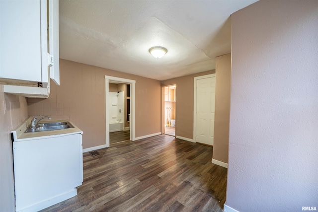 interior space featuring a sink, baseboards, and dark wood-type flooring