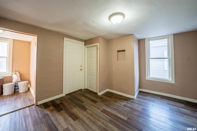 interior space with baseboards, a textured ceiling, and dark wood-style floors