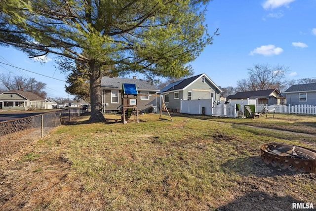 view of yard featuring a playground, a fenced backyard, a residential view, and an outdoor fire pit