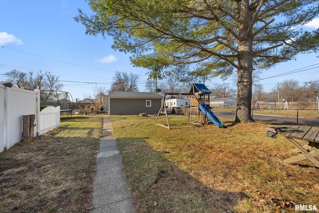 view of yard featuring fence, a trampoline, an outbuilding, and a playground