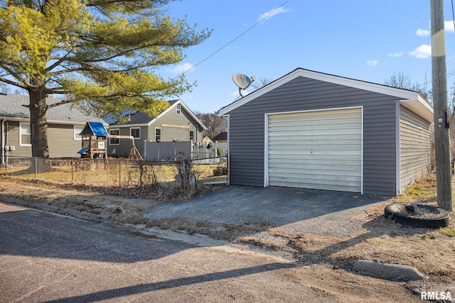 detached garage featuring aphalt driveway and fence