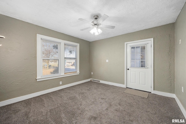 empty room featuring visible vents, a textured ceiling, a ceiling fan, and a textured wall