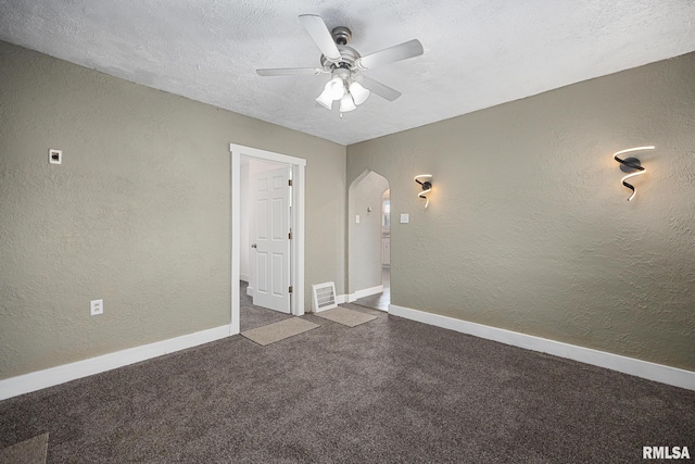 carpeted spare room featuring a textured ceiling, a textured wall, arched walkways, and ceiling fan