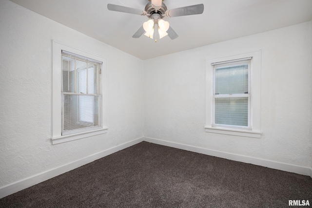 unfurnished room featuring dark colored carpet, baseboards, and a textured wall