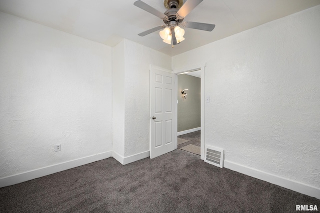 unfurnished room featuring a textured wall, visible vents, dark colored carpet, and baseboards