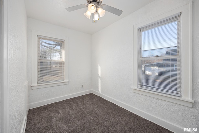 empty room with dark carpet, a ceiling fan, baseboards, and a textured wall