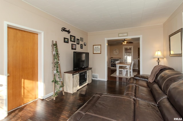 living area featuring dark wood finished floors, baseboards, visible vents, and ceiling fan