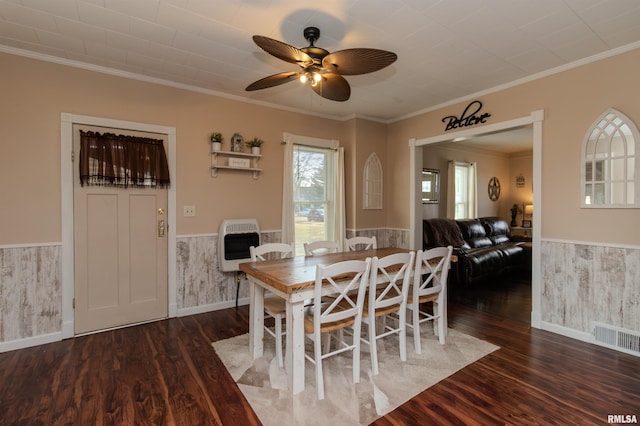 dining area featuring visible vents, heating unit, wood finished floors, and wainscoting