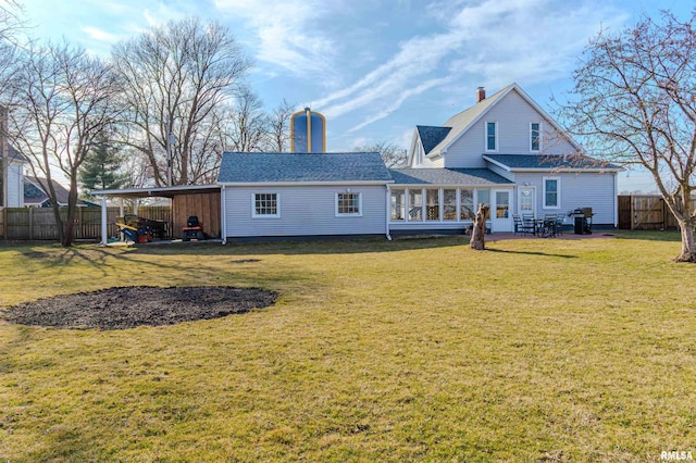 rear view of house with fence, a shingled roof, a chimney, a carport, and a lawn