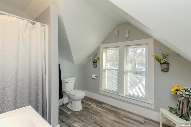 full bath featuring lofted ceiling, toilet, wood finished floors, and a wealth of natural light