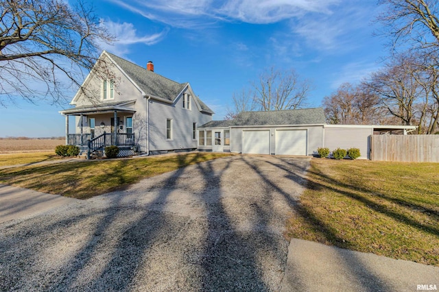 view of side of home with fence, driveway, a porch, an attached garage, and a lawn