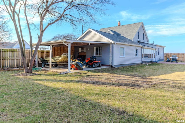 back of property featuring a patio area, a lawn, a shingled roof, and fence