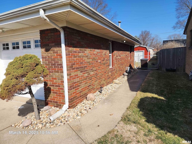 view of property exterior featuring an attached garage, fence, and brick siding