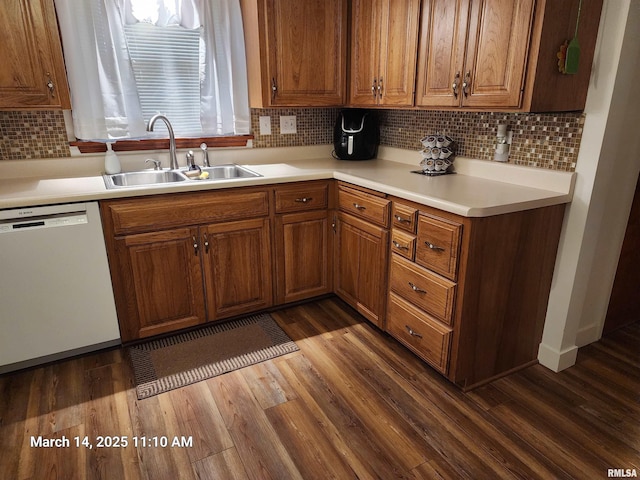 kitchen with brown cabinetry, dark wood-style floors, a sink, light countertops, and dishwasher