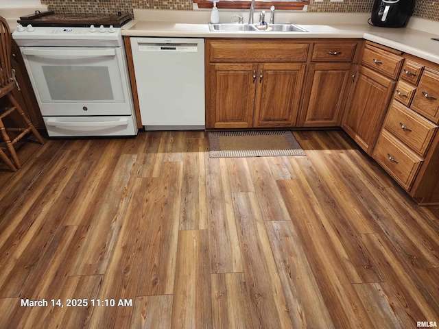 kitchen with decorative backsplash, white appliances, wood finished floors, and a sink