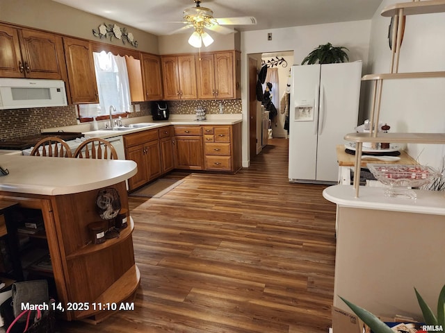 kitchen featuring white appliances, brown cabinetry, open shelves, a sink, and dark wood-type flooring