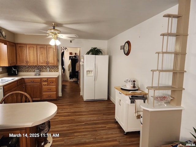 kitchen featuring ceiling fan, light countertops, dark wood-type flooring, white fridge with ice dispenser, and backsplash