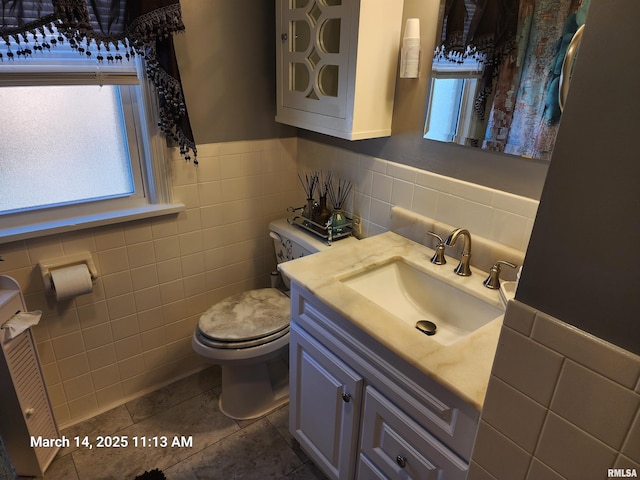 bathroom featuring tile walls, wainscoting, toilet, and vanity