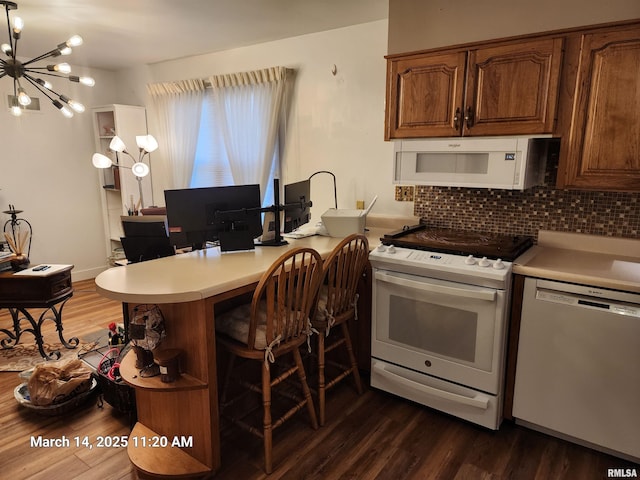 kitchen featuring white appliances, tasteful backsplash, dark wood-style floors, and light countertops