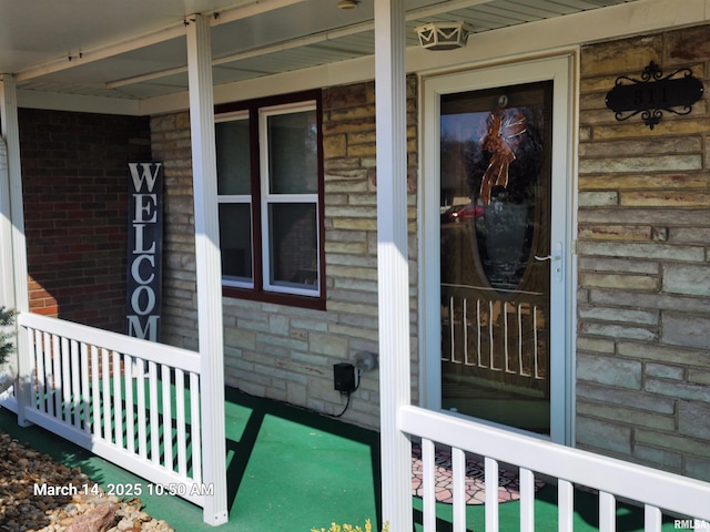 view of exterior entry featuring a porch and stone siding