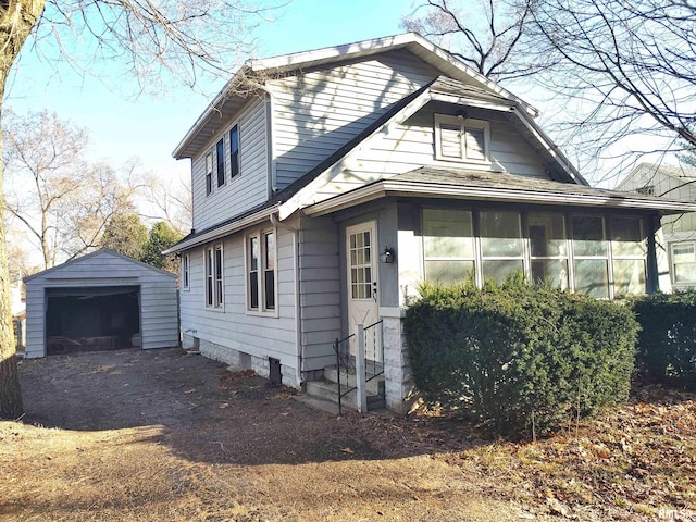 view of side of property featuring driveway, a sunroom, entry steps, an outdoor structure, and a garage