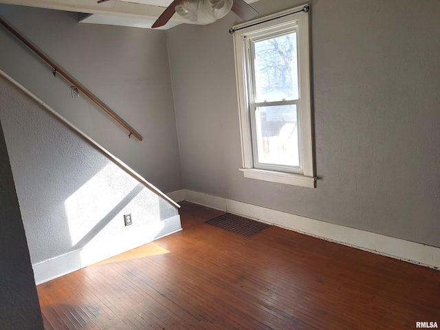 unfurnished room featuring hardwood / wood-style flooring, a ceiling fan, visible vents, and baseboards