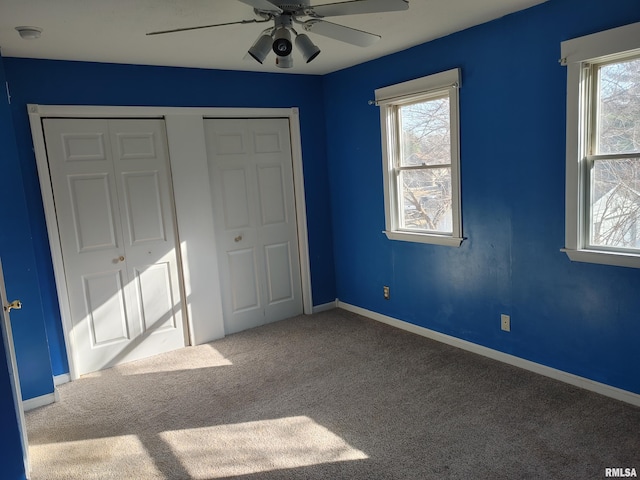 unfurnished bedroom with multiple windows, carpet flooring, a ceiling fan, and baseboards